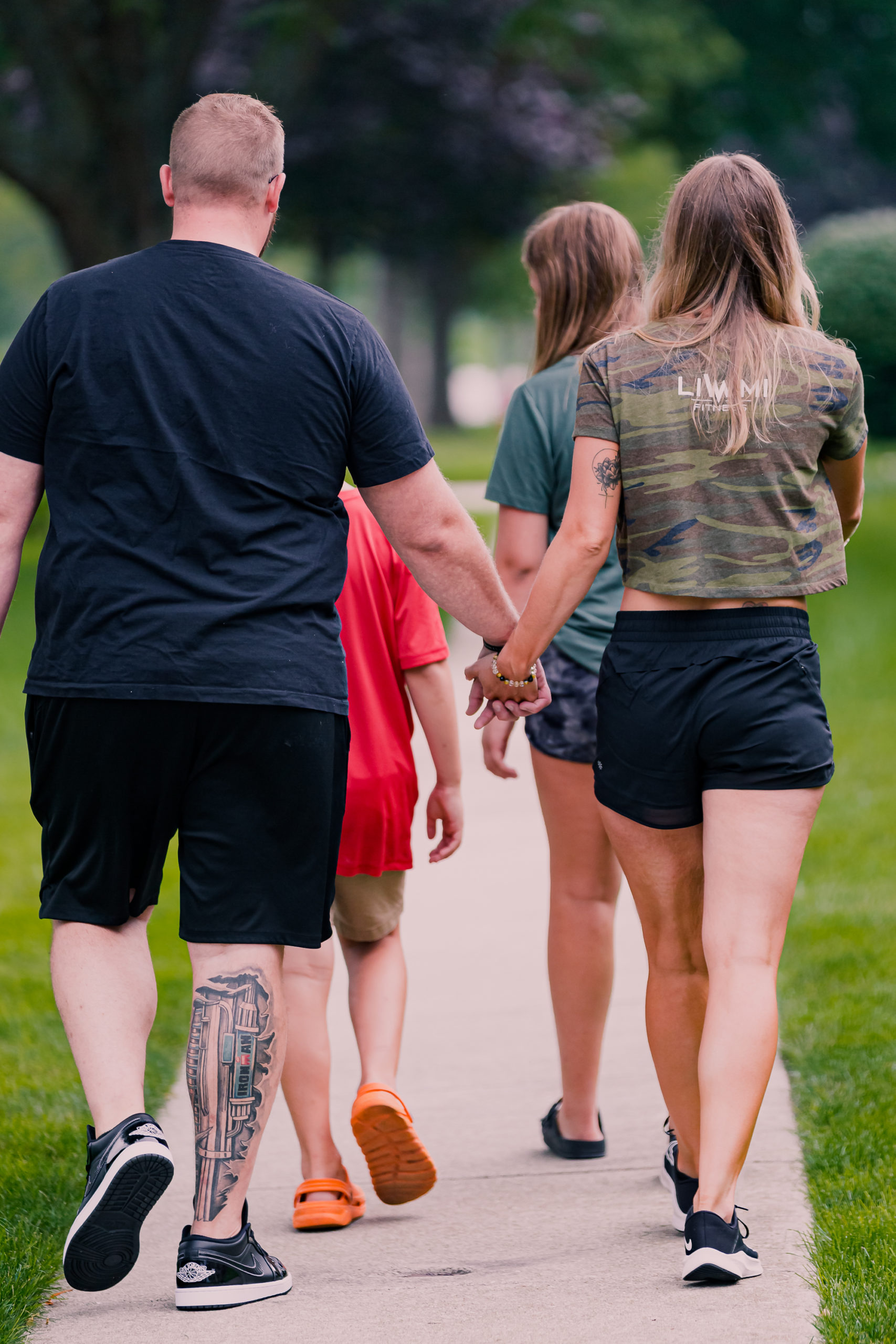 Couple Holding Hands Walking Down Sidewalk with Kids in Front of Them