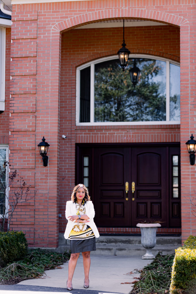 Woman Crossing Arms in Front of Entryway to Big House