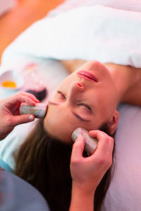 Woman giving a stone massage to another woman