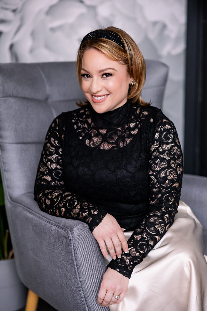 Vibrant brand photo of a woman in a black lace dress sitting in a velvet chair, taken by This Way to Fabulous