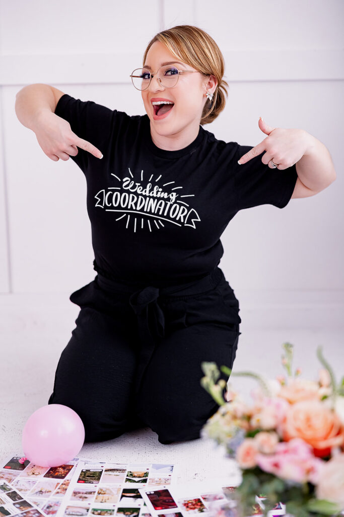 Vibrant and fun brand photo of a woman sitting and pointing to the words on her t-shirt "wedding coordinator", taken by This Way to Fabulous