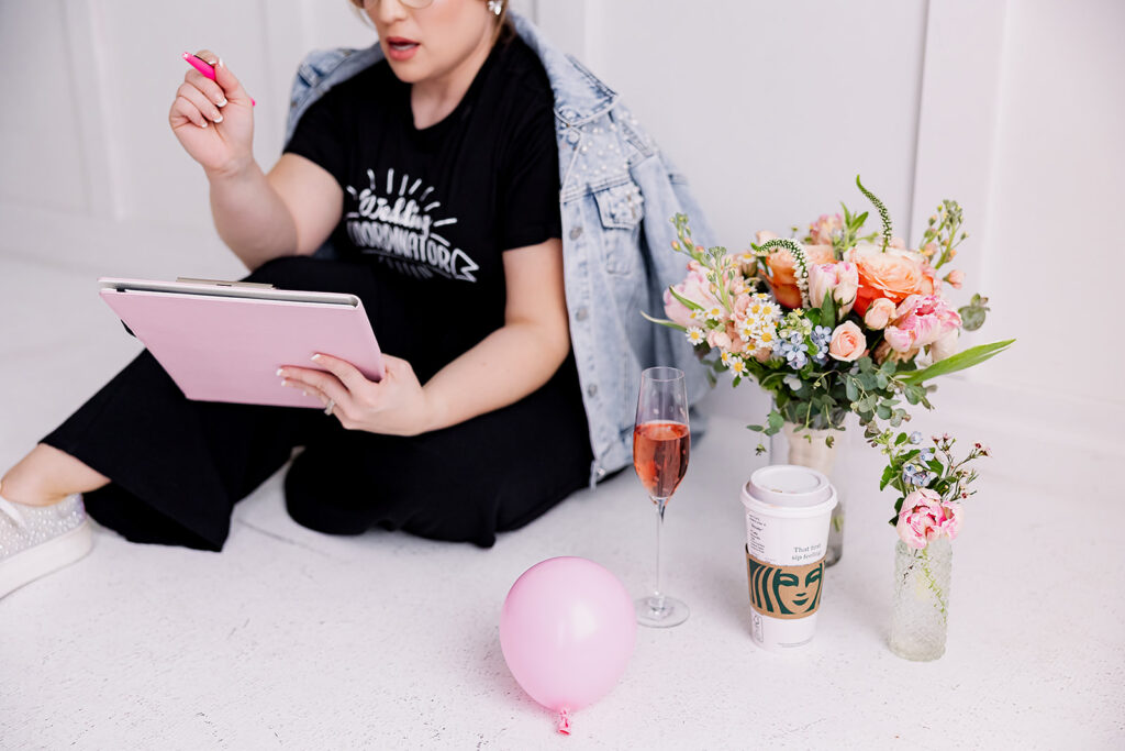 Vibrant and fun brand photo of a woman in a beaded jean jacket surrounded by flowers, balloons, and mood boards, taken by This Way to Fabulous