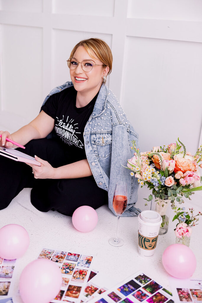 a woman sitting on the floor holding a folder surrounded by balloons and flowers