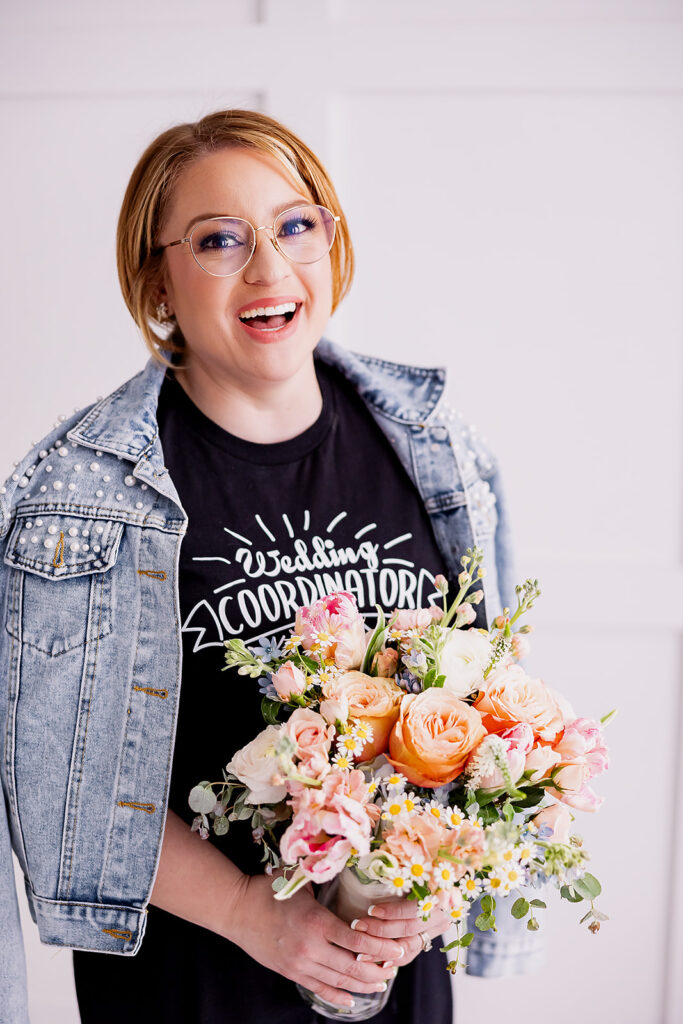 Vibrant and fun brand photo of a woman wearing a beaded jean jacket holding a colorful bouquet of flowers, taken by This Way to Fabulous