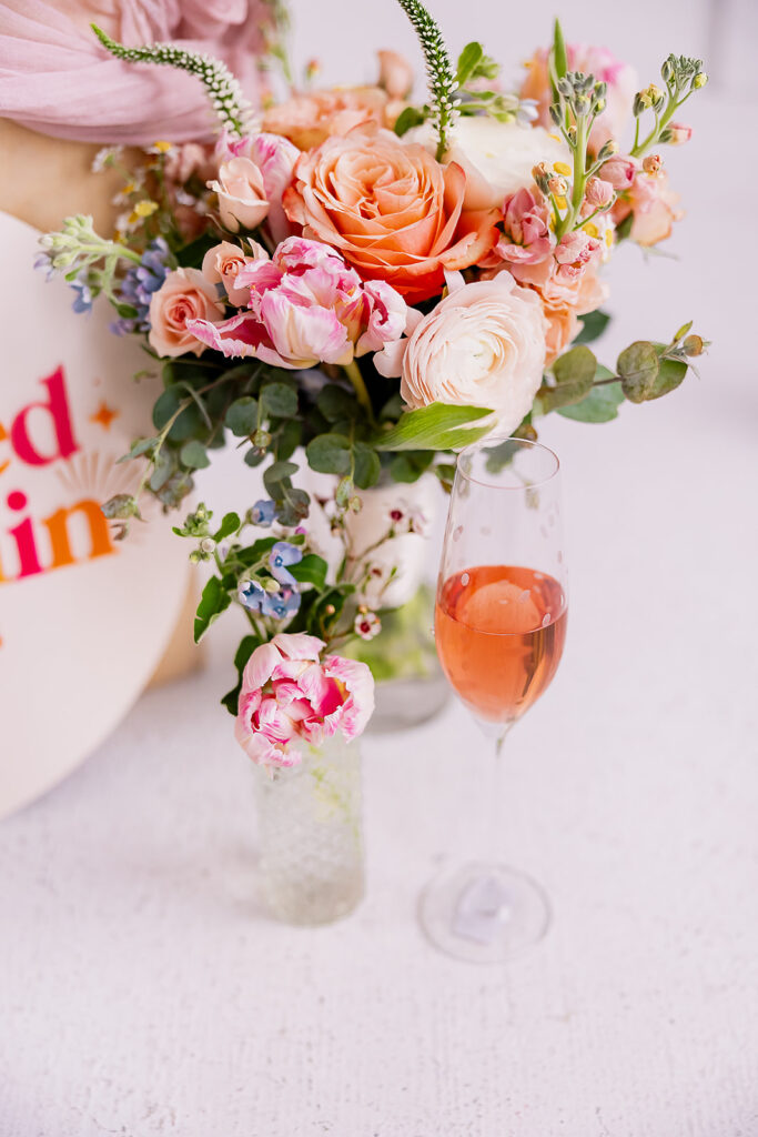 Vibrant and fun brand photo of a bouquet of flowers and a glass of champagne, taken by This Way to Fabulous