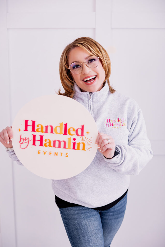 Vibrant and fun brand photo of a woman holding a "Handled by Hamlin" logo sign, taken by This Way to Fabulous