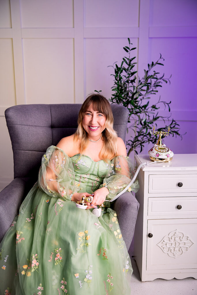 woman in a green whimsical dress holding an antique telephone