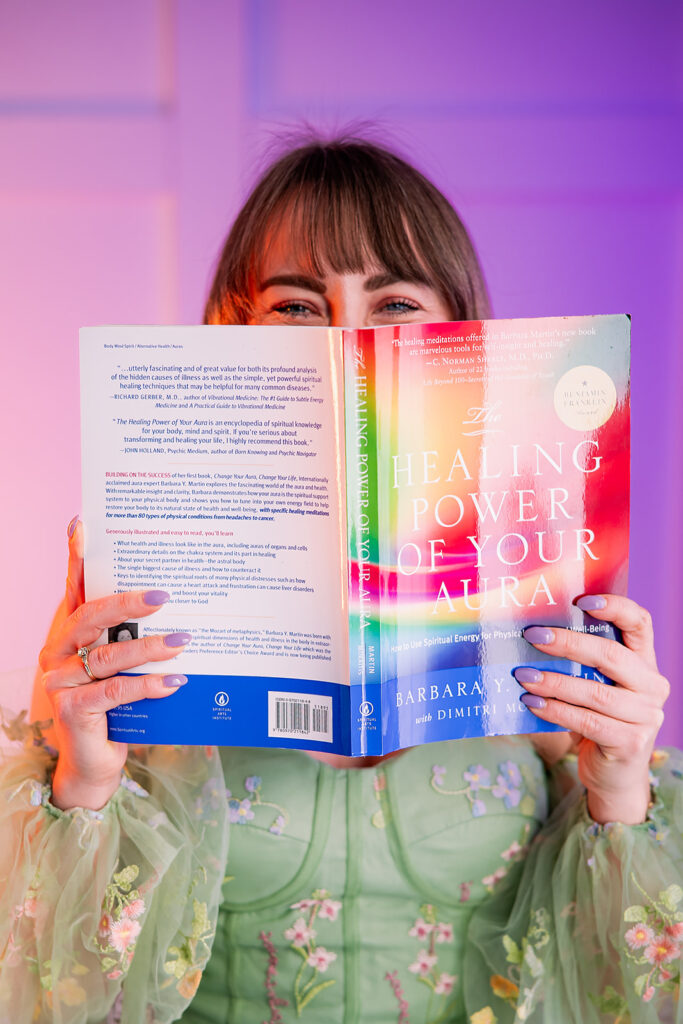 woman holding the book "Healing Power of Your Aura" in front of her face
