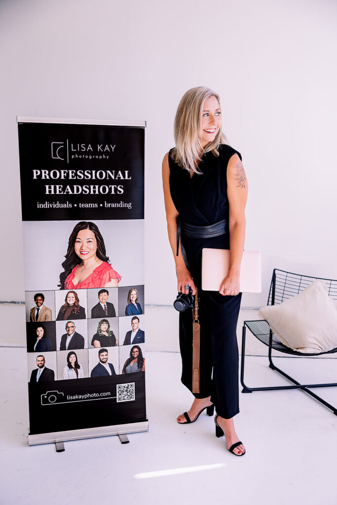 photographer standing by a sign advertising her professional headshot services
