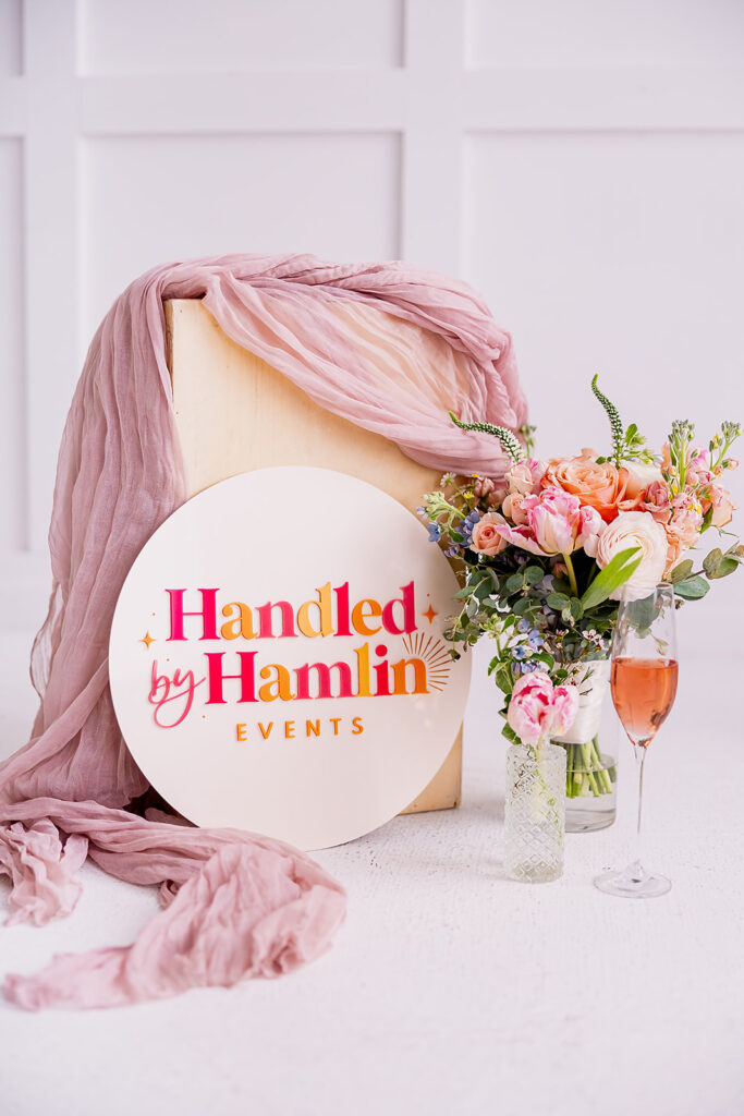 Handled by Hamlin Events sign with wedding flowers and champagne