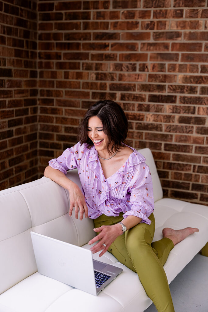 a woman dressed in professional clothing posing for a branding photo on a couch