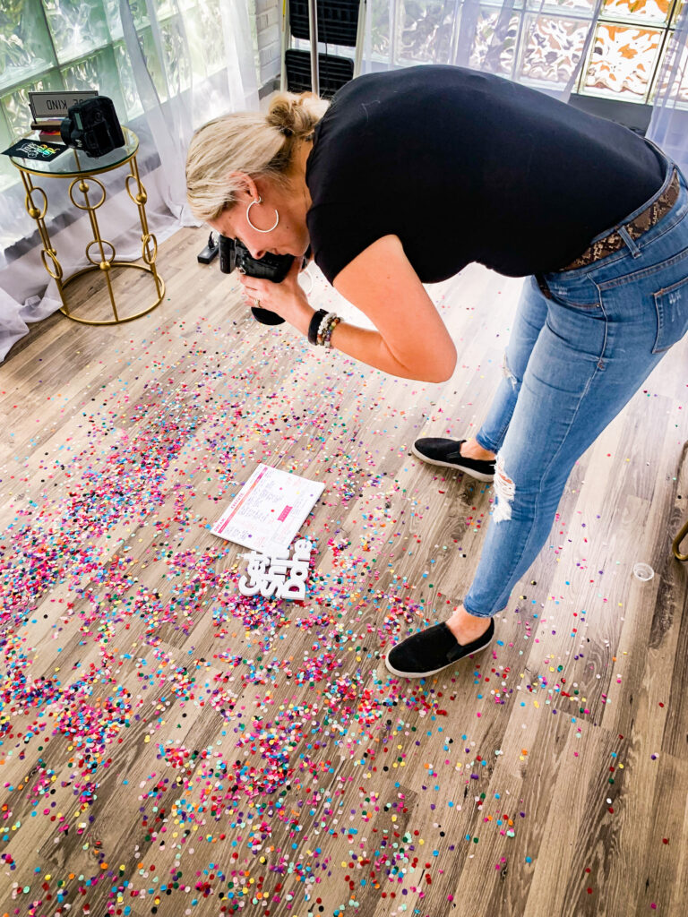 photographer taking a flat lay photo on the ground with confetti and brand props