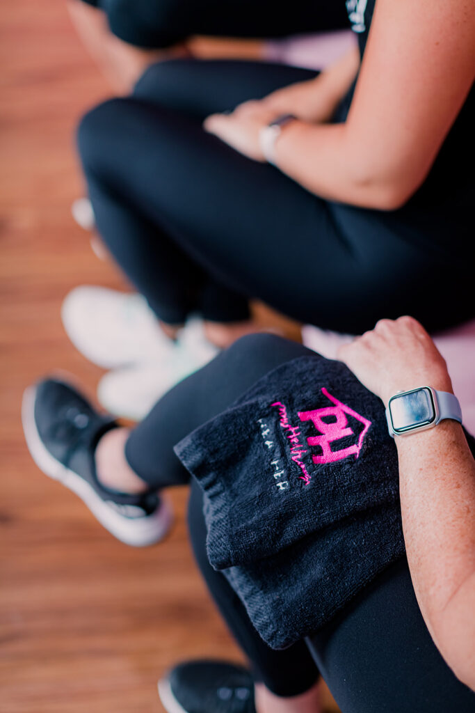 Black PowHerHouse Fitness sweat towel on a woman's leg