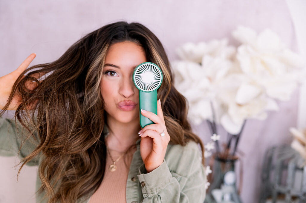 Branding detail image of a brunette woman holding a lash fan in front of her eye
