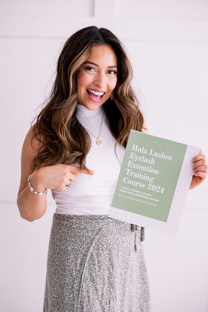 Branding detail image of a brunette woman pointing to her lash extension training workbook