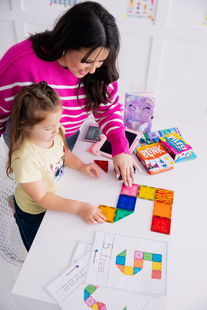 personal branding photo of Jacquelin Castillo of Mom Like a Boss wearing pink with her daughter playing with toys photographed by This Way to Fabulous