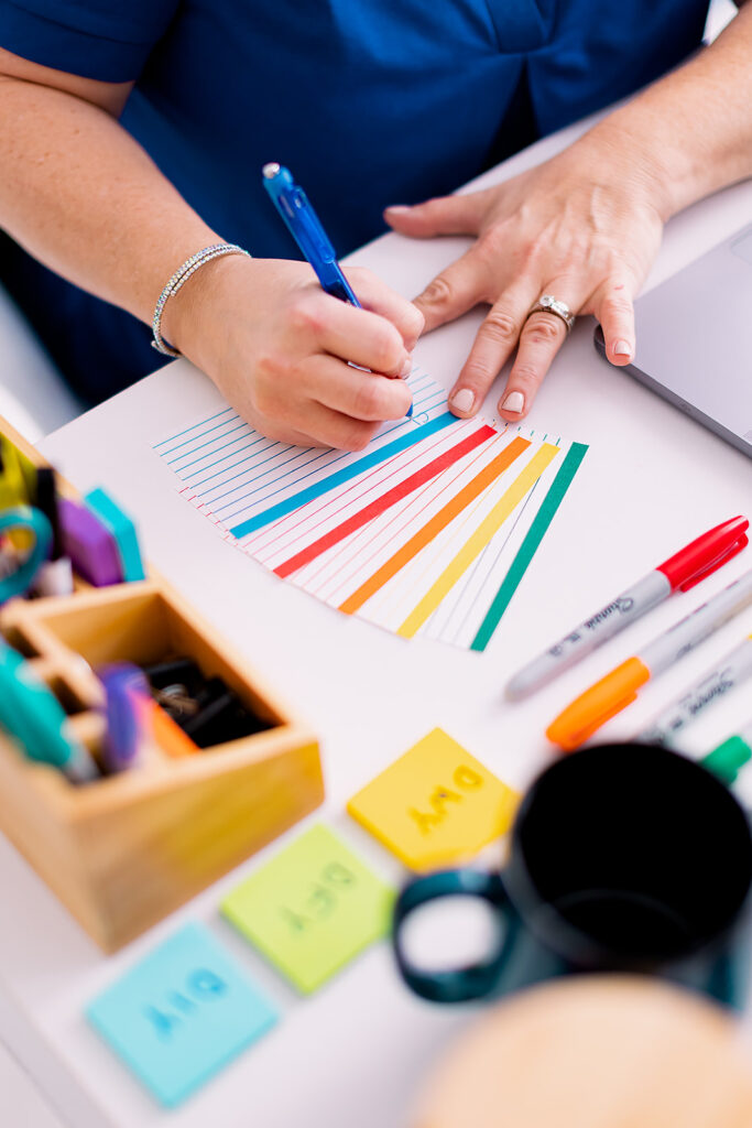 woman writing on brightly colored note pads during her professional organizer branding photoshoot by This Way to Fabulous
