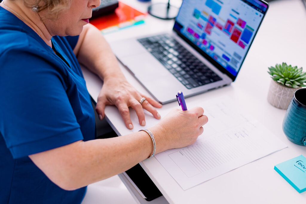 Amy from Clutter Care writing on a piece of paper during her professional organizer branding photoshoot by This Way to Fabulous